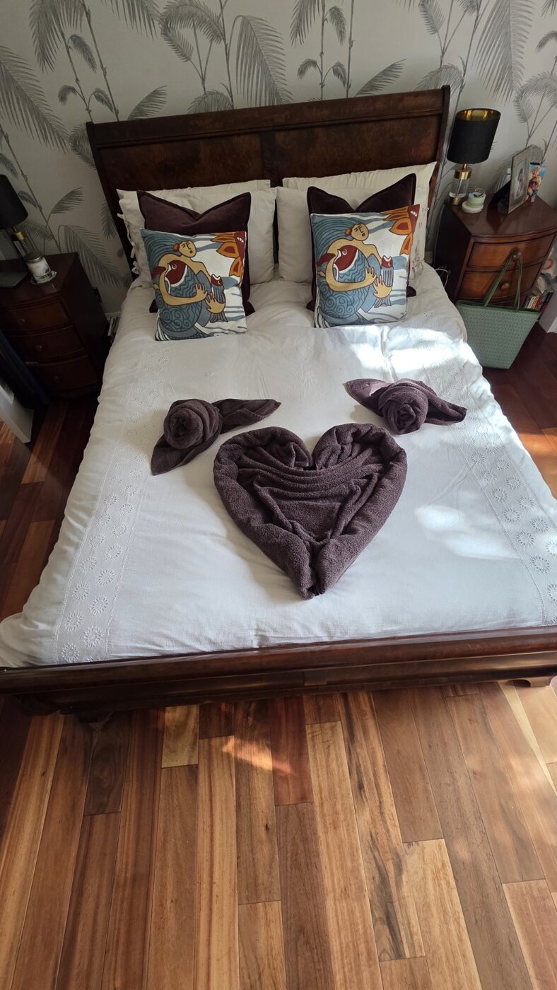 Purple towels folded into a heart and roses on a freshly made bed